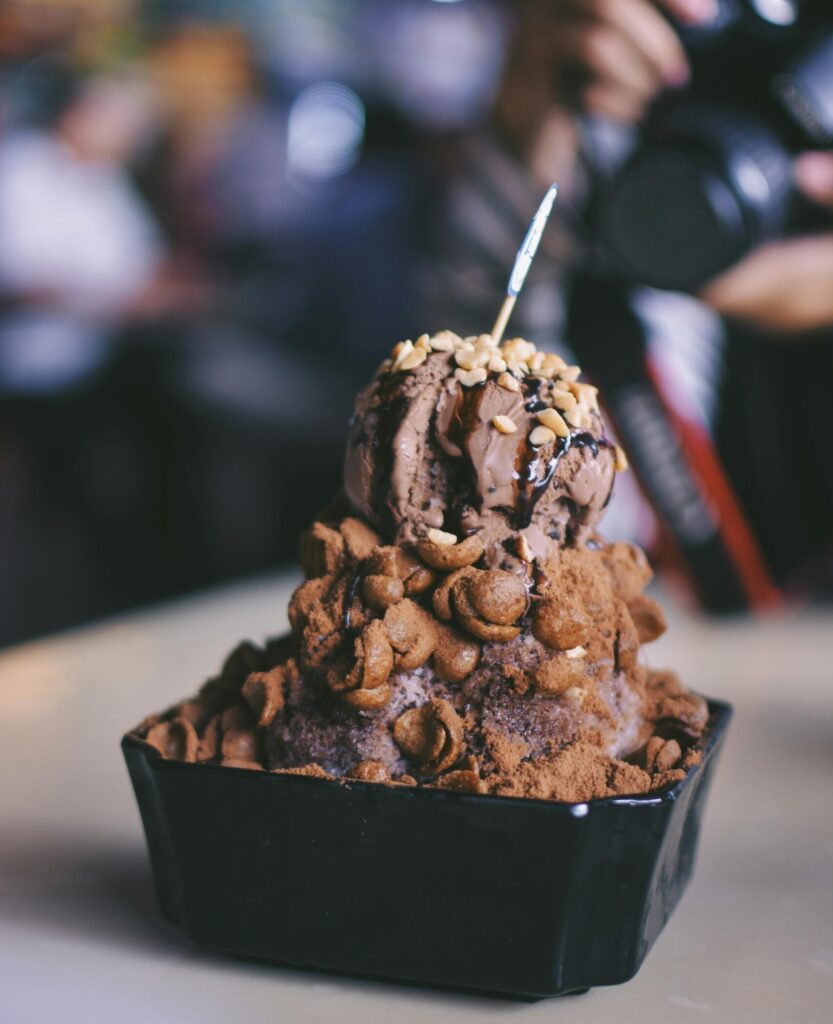 Indulge in creamy chocolate ice cream topped with crunchy nuts and syrup, perfect for dessert lovers.